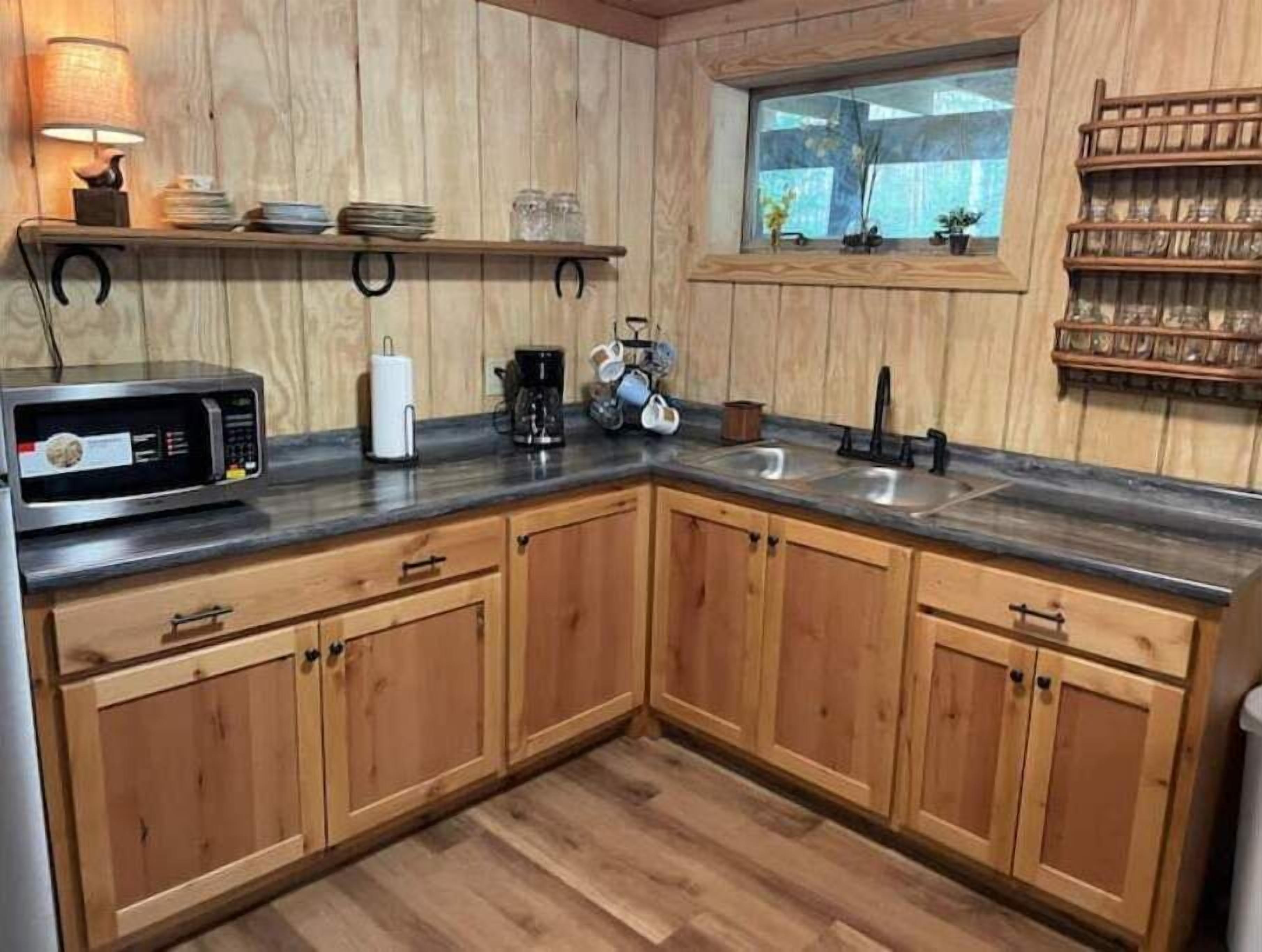 A kitchen with wooden cabinets, a microwave, a coffee maker, and a window with a view.