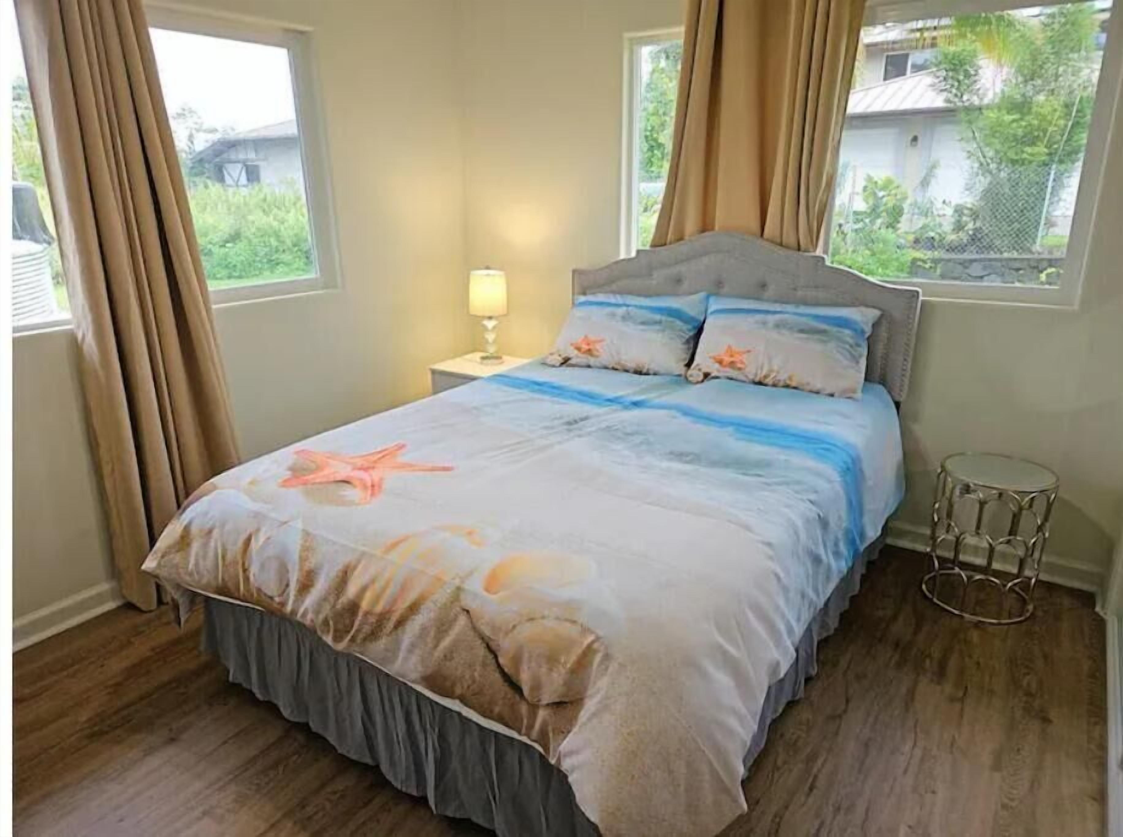 A bedroom with a bed, curtains, a nightstand, and a lamp.