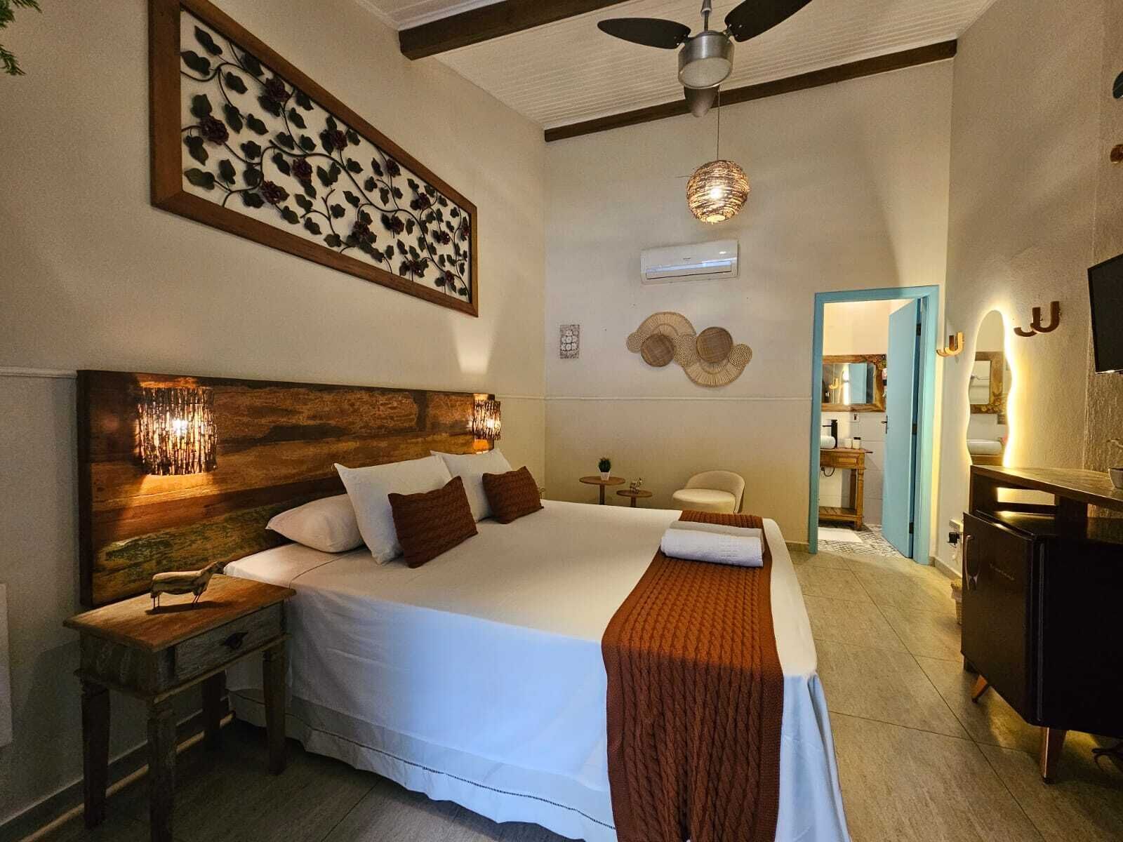 A spacious bedroom with a large bed, a wooden headboard, a ceiling fan, and a wall-mounted air conditioner.