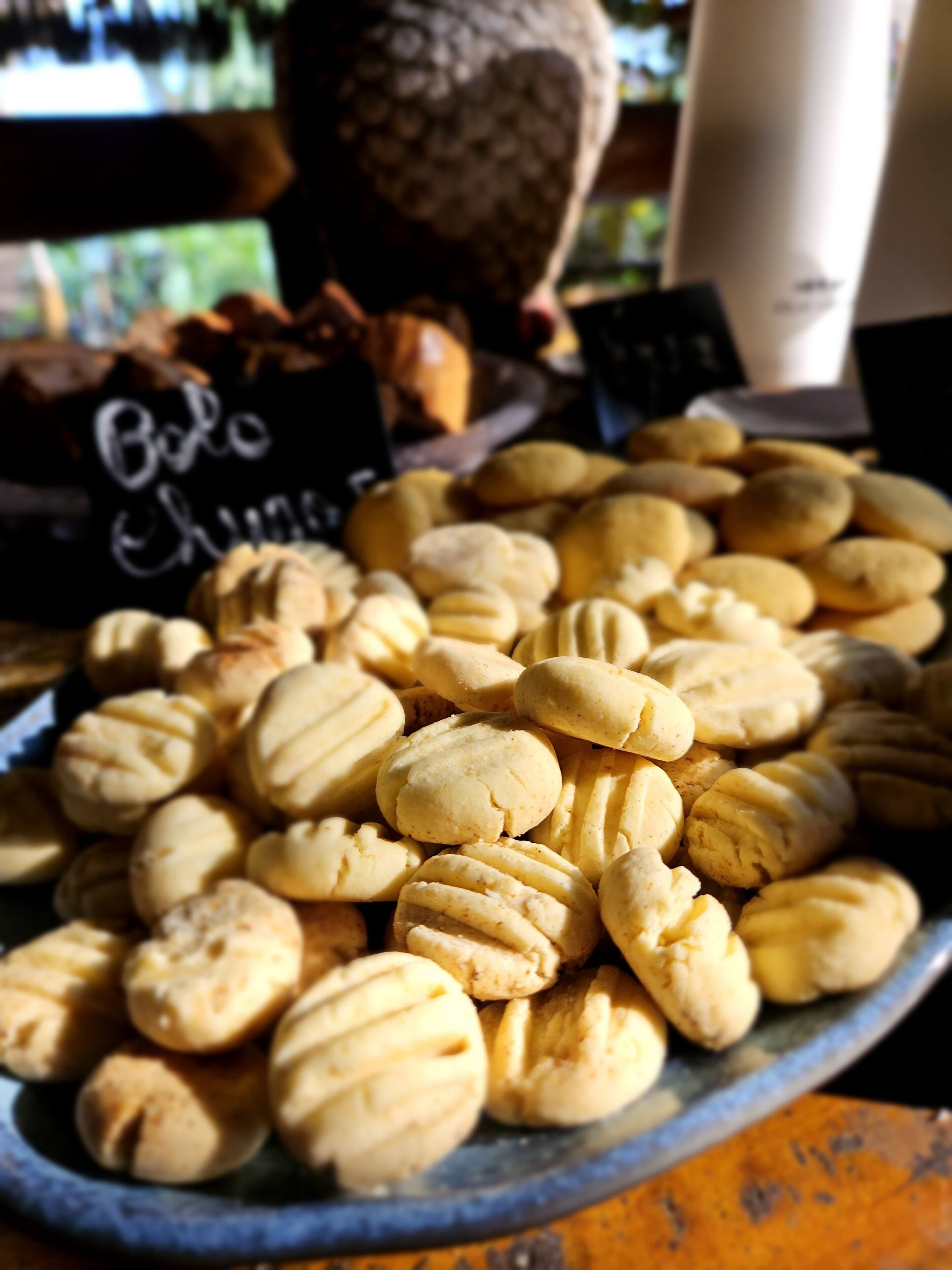 Um prato de biscoitos redondos, dourados e com padrão cruzado, apresentado em um prato azul.