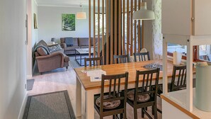 Cozinha moderna com mesa de jantar de madeira, cadeiras de madeira escura e uma janela grande.