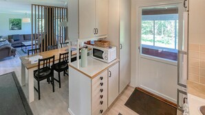 Uma cozinha compacta com micro-ondas, mini-geladeira e um espaço de refeições com mesa e cadeiras.