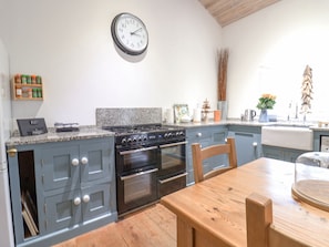 A kitchen with a granite countertop, a stove, oven, and a wooden dining table.