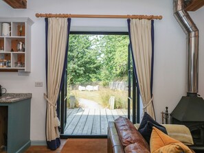 Una habitación acogedora con un banco de madera, chimenea y vistas a un jardín a través de un ventanal.
