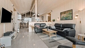 Un salon moderne avec un canapé en cuir noir, une table basse et un téléviseur fixé au mur.