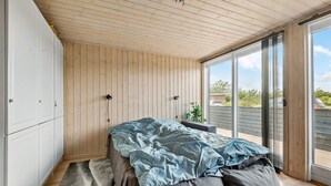 Une chambre à coucher comprenant un lit, une armoire et une porte-fenêtre coulissante donnant sur un balcon.