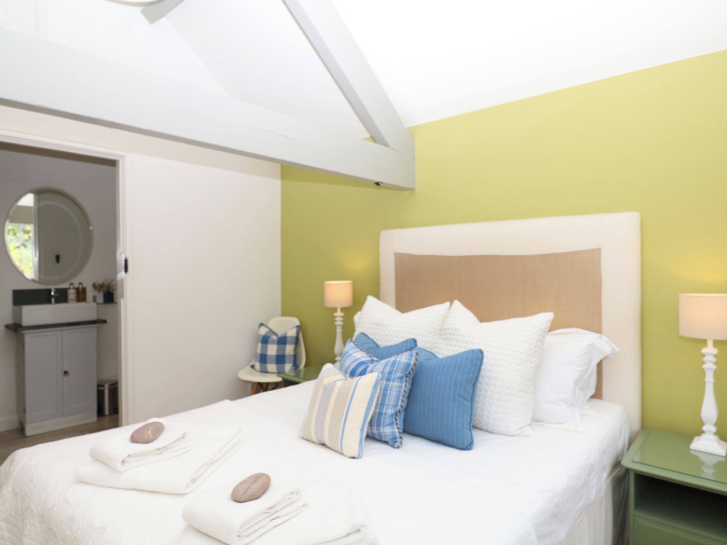 A hotel room with a bed, bedside table, lamp, and a view of the bathroom.