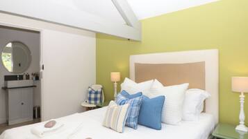 A hotel room with a bed, bedside table, lamp, and a view of the bathroom.
