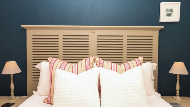 A bed with a headboard, two bedside lamps, and a framed picture on the wall. - Apple Mill (Ottery St Mary)