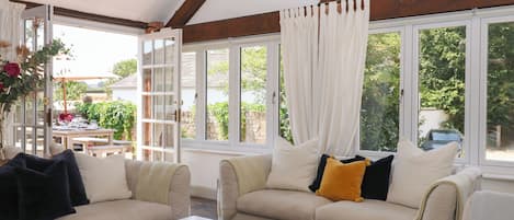 A room with a white sofa, a white coffee table, and a window with curtains.