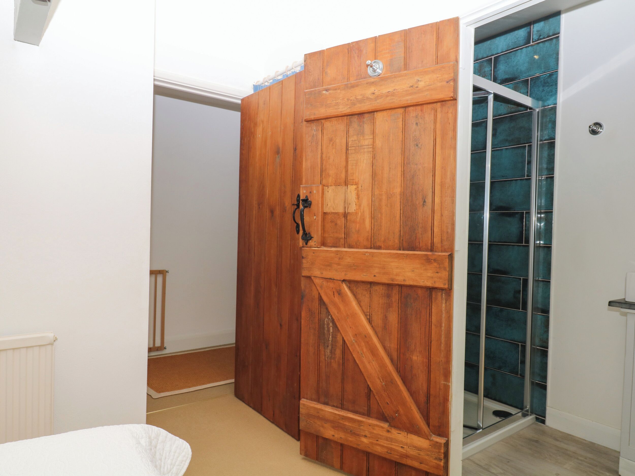Une pièce avec une porte en bois, un espace de douche en verre et un radiateur blanc.
