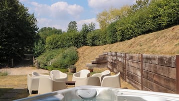 Un jacuzzi con valla de madera y sillas en un jardín.