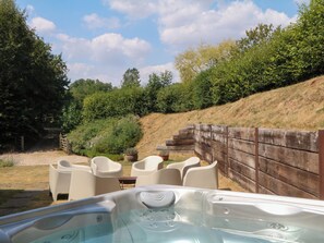 Un jacuzzi con valla de madera y sillas en un jardín.