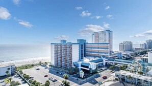 Un hôtel moderne à plusieurs étages, doté d’un parking et offrant une vue sur la plage.