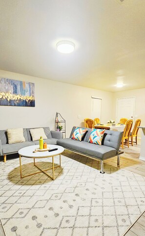 Relax in this stylish living room with a comfortable sofa, dining area, and large abstract art piece.