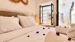 Una habitación de hotel con una cama grande, una ventana con vistas y espejos decorativos en la pared.