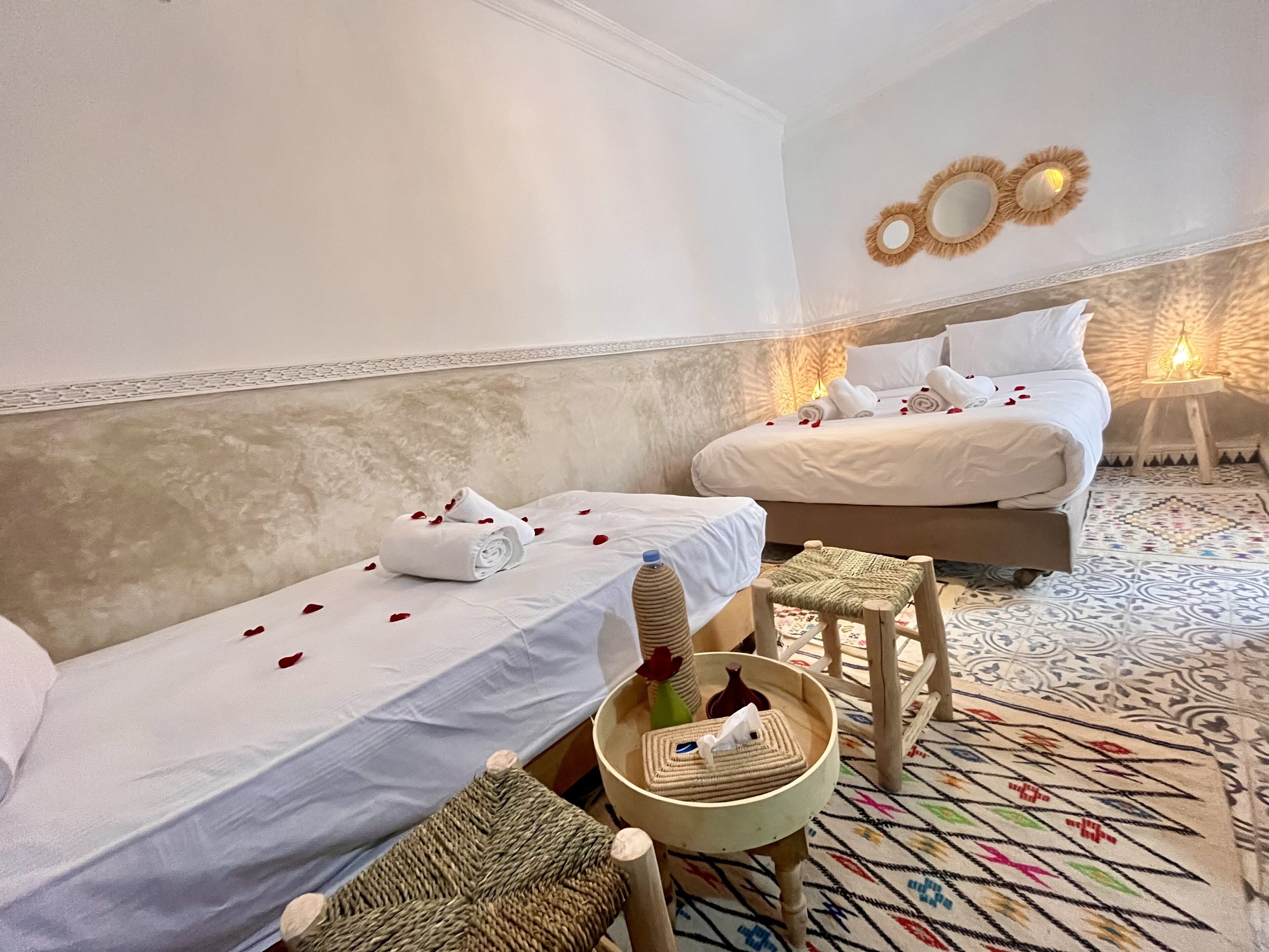 Habitación de hotel con dos camas, una mesita con una cesta y un detalle decorativo en la pared.