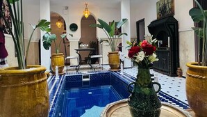 Un patio interior con piscina, plantas en macetas y un comedor.