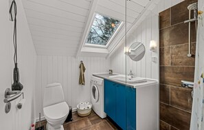 A compact bathroom with a skylight, a washing machine, a toilet, and a shower area. - 3 bedroom cozy home in Toftlund (Toftlund)