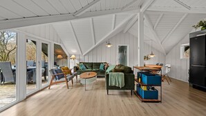 Um quarto amplo com teto alto, janelas grandes e uma área de estar aconchegante com sofá e poltronas.