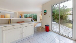 A modern kitchen with a large island, a sliding glass door leading to a patio, and a view of greenery outside. - Lovely home in Les Mathes with WiFi (Les Mathes)