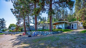 A row of cabins with a stone retaining wall, a gravel path, and a grassy area with chairs.