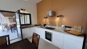 Une cuisine moderne avec des meubles blancs, une cuisinière à gaz et une machine à café.