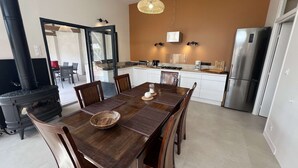 Une cuisine moderne avec un coin repas, comprenant une grande table en bois, des chaises, une cuisinière et un réfrigérateur.