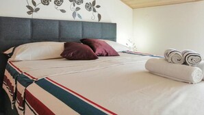 Una cama bien hecha con una colcha a rayas, dos almohadas y toallas enrolladas al lado.