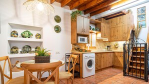 Eine Küche mit Holzschränken, einer Waschmaschine und einem Essbereich mit Stühlen und einem Tisch.