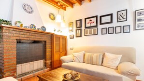 Ein Wohnzimmer mit Kamin aus Backstein, einem weißen Sofa und einem Holztisch.