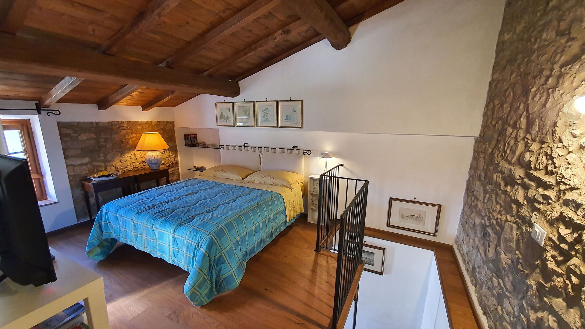 Una camera da letto con un letto, una scrivania, una lampada e un muro in pietra.