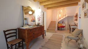 Un salon chaleureux avec une commode en bois, un grand miroir et un escalier menant à une autre pièce.