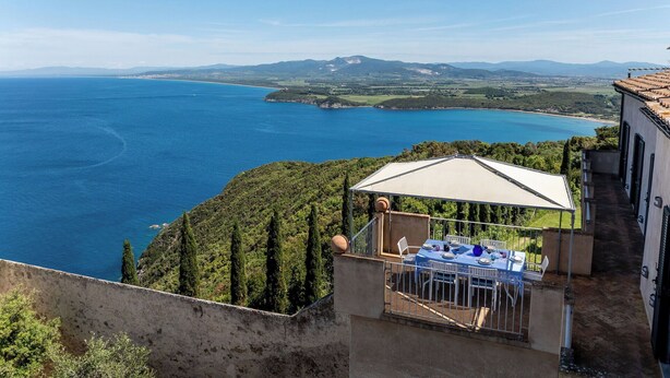 Una terrazza con tavolo e sedie che si affaccia su un paesaggio costiero.