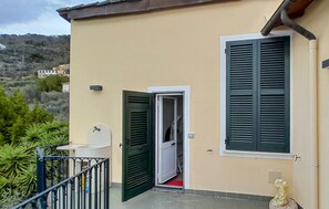 A building with a balcony, a door, and a window with shutters.