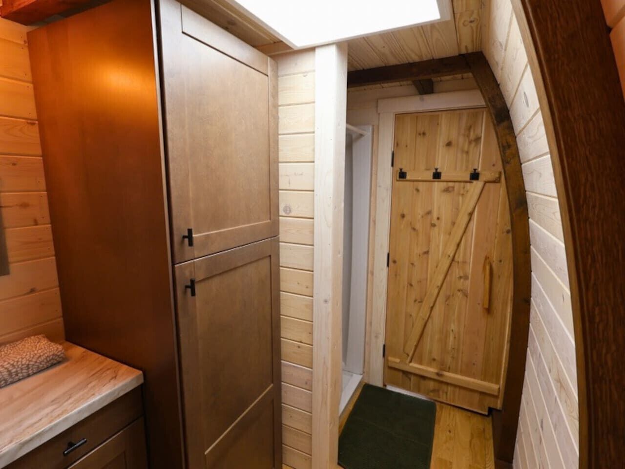 A narrow hallway with wooden walls and a door with a diagonal handle.