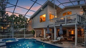 A two-story house with a swimming pool, outdoor seating, and string lights.