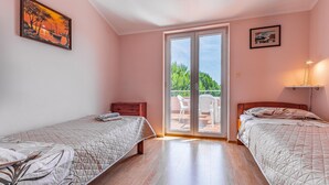 Ein Schlafzimmer mit zwei Betten, einer Glasschiebetür zu einem Balkon und Bildern an den Wänden.