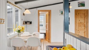 En matplats med ett bord, stolar, en vas med blommor och en fruktskål.
