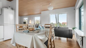 Eine moderne Küche mit Essbereich, Holzböden und großen Fenstern mit Blick ins Freie.