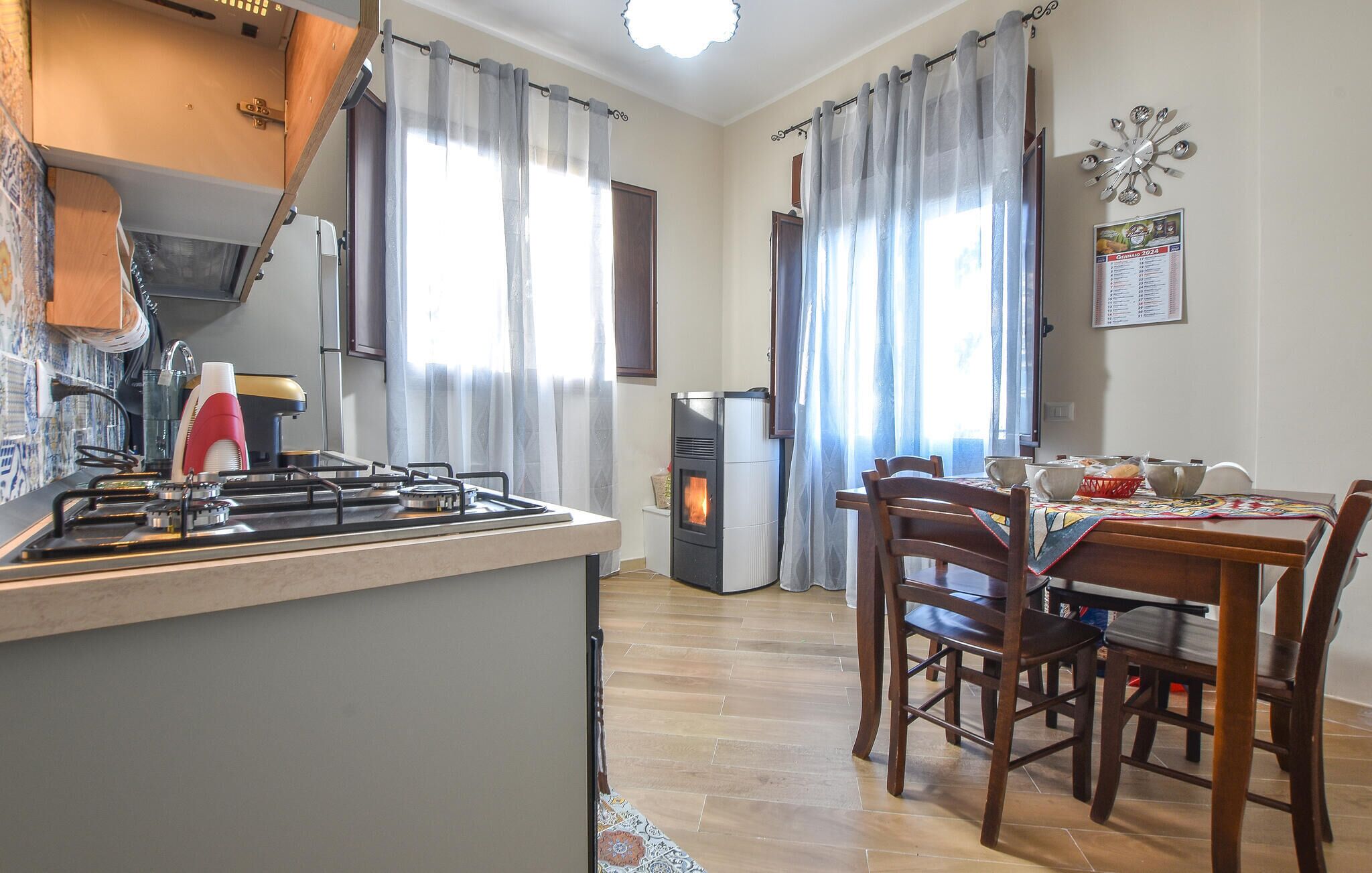 Una cuina amb fogons, un frigorífic i una zona de menjador amb taula i cadires.