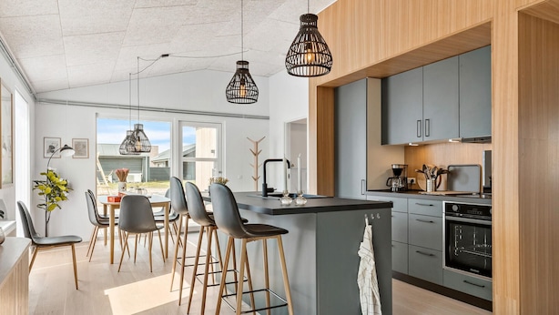 A modern kitchen with a central island, bar stools, and pendant lighting.
