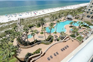 A resort with a pool area, palm trees, and a beach view. - Indigo West Oceanfront Condo | Resort Amenities | My Beach Getaways (Pensacola)