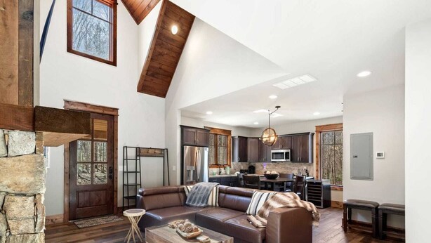 A spacious living room with a large sectional sofa, a wooden coffee table, and a stone accent wall.