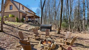 A cabin with a deck, outdoor seating, and a fire pit.