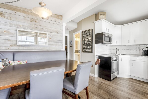 A modern kitchen with white cabinets, a black stove, and a microwave. - Secluded Cabin on Lake Okanagan (West Kelowna)