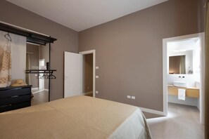 Une chambre à coucher comprenant un lit, une commode, un miroir et une porte donnant sur une salle de bain.