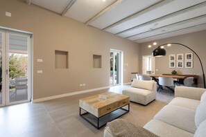 A spacious living room with a large sofa, a coffee table, and a dining area with a table and chairs. - WePuglia - Dimora Montaltino (Castellana Grotte)