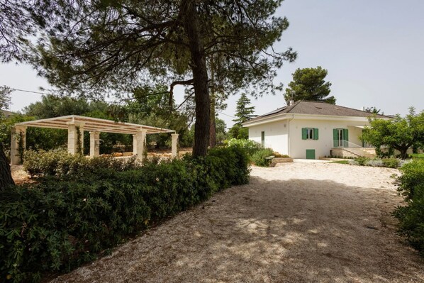 Ein Haus mit überdachter Terrasse, einem Schotterweg und einem gepflegten Garten.