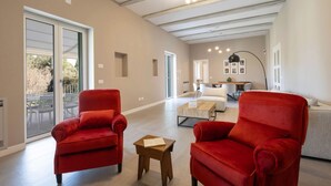 A spacious living area with red armchairs, a wooden coffee table, and a white sofa. - WePuglia - Dimora Montaltino (Castellana Grotte)